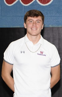 a young man in a white shirt standing in front of a wall